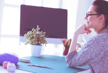 Moda tasarımcıları stüdyoda çalışıyor. Masanın üzerinde oturuyorlar..