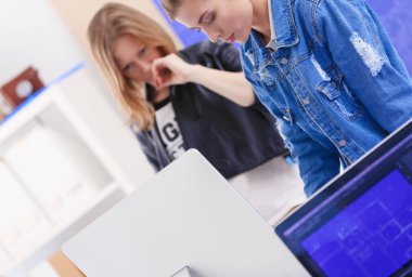 Enstrümanlar, planlar ve dizüstü bilgisayarlarla masanın yanında duran genç bir kadın..