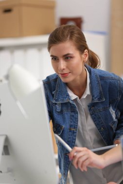 Masanın yanında duran iki genç kadın enstrüman, plan ve dizüstü bilgisayarla.