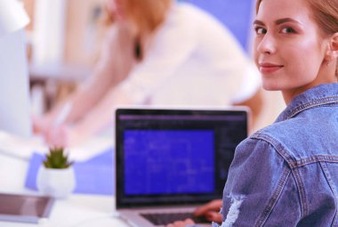 İki genç kadın masada enstrümanlar, planlar ve dizüstü bilgisayarlarla oturuyor..