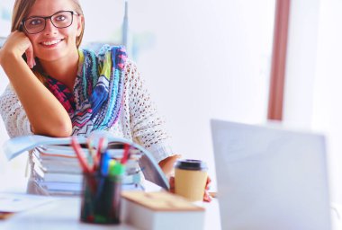 Kitapların arasında masa başında oturan genç bir kadın.