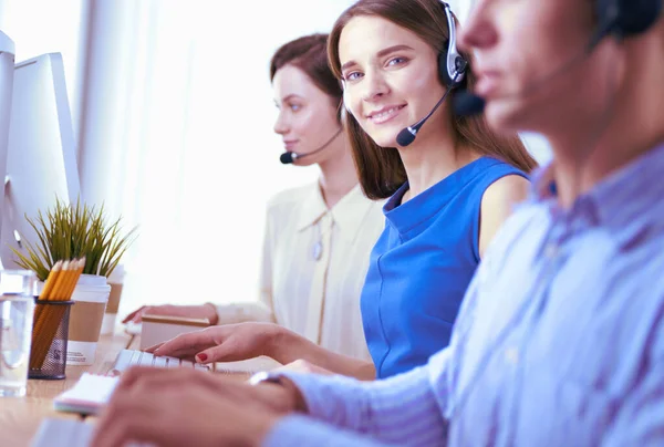 Leende medarbetare på callcenter sitter i linje med sitt headset — Stockfoto