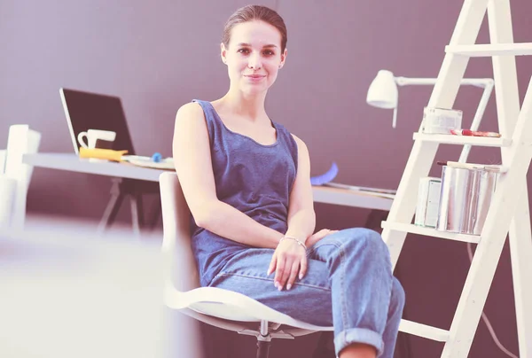 Jonge vrouw zit aan het bureau met instrumenten, plan en laptop. — Stockfoto