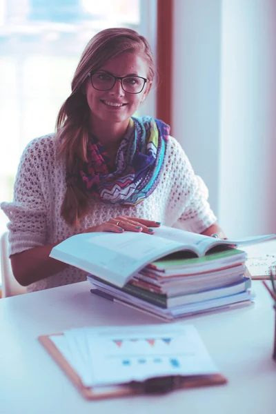 Młoda kobieta siedząca za biurkiem wśród książek. Student — Zdjęcie stockowe