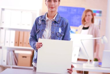 Masanın yanında duran iki genç kadın enstrüman, plan ve dizüstü bilgisayarla.