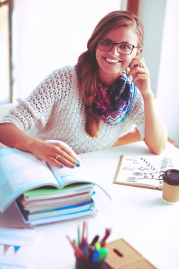 Kitapların arasında masa başında oturan genç bir kadın.