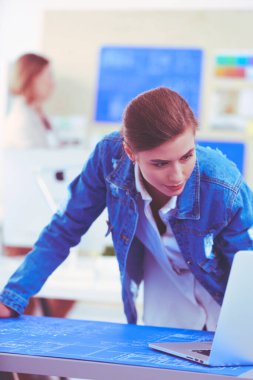 Masanın yanında duran iki genç kadın enstrüman, plan ve dizüstü bilgisayarla.