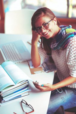 Kitapların arasında masa başında oturan genç bir kadın.