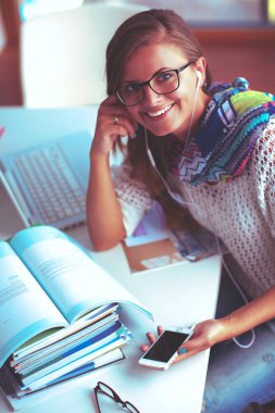 Kitapların arasında masa başında oturan genç bir kadın.