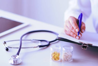 Kadınların elleri bir kağıt üzerinde kalemle yazı yazarlar.