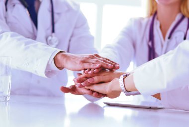 Doktorlar el ele tutuşup yakın çekim yapıyor.