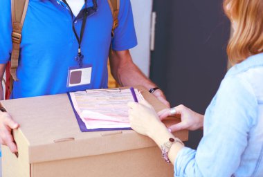 Mavi üniformalı gülümseyen kurye servis konseptine paket kutusu teslim eden teslimatçı. Mavi üniformalı gülümseyen teslimatçı.