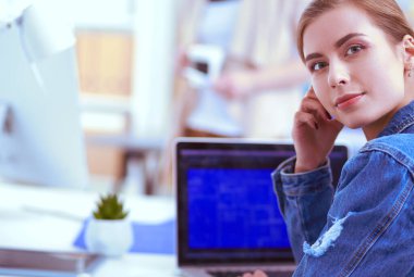 İki genç kadın masada enstrümanlar, planlar ve dizüstü bilgisayarlarla oturuyor..