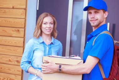 Mavi üniformalı gülümseyen kurye servis konseptine paket kutusu teslim eden teslimatçı. Mavi üniformalı gülümseyen teslimatçı.