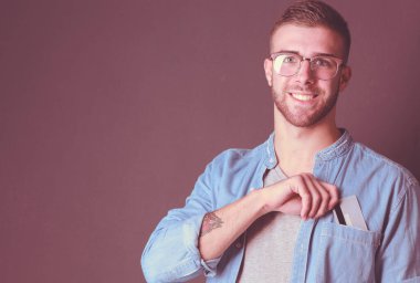 Gri arka planda duran bir kredi kartı tutan genç adam. Genç girişimci..