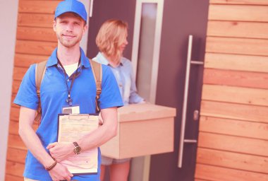 Mavi üniformalı gülümseyen kurye servis konseptine paket kutusu teslim eden teslimatçı. Mavi üniformalı gülümseyen teslimatçı.