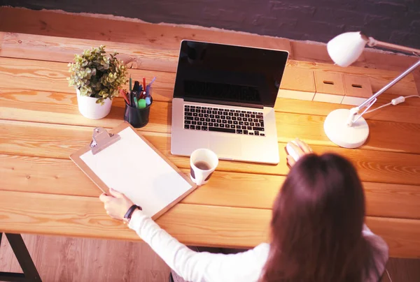 Jeune femme travaillant assise à un bureau — Photo