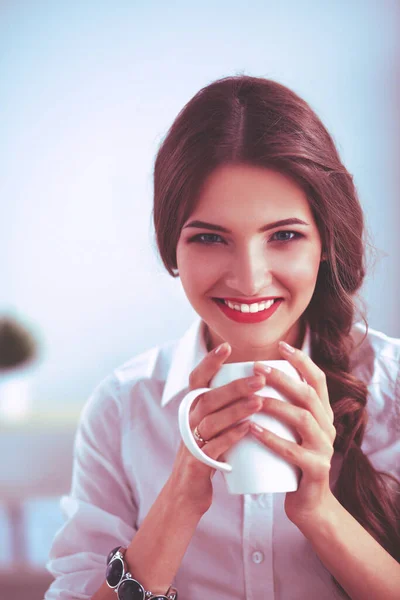 Attractive businesswoman sitting on desk in the office — Stock Photo, Image