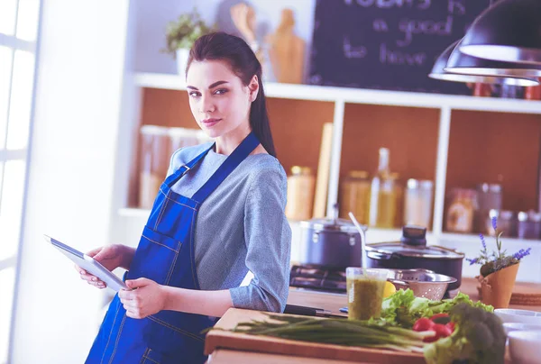 Mujer joven usando una tableta para cocinar en su cocina — Foto de Stock