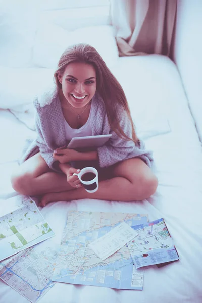 Entspannte junge Frau sitzt mit einer Tasse Kaffee und digitalem Tablet im Bett — Stockfoto