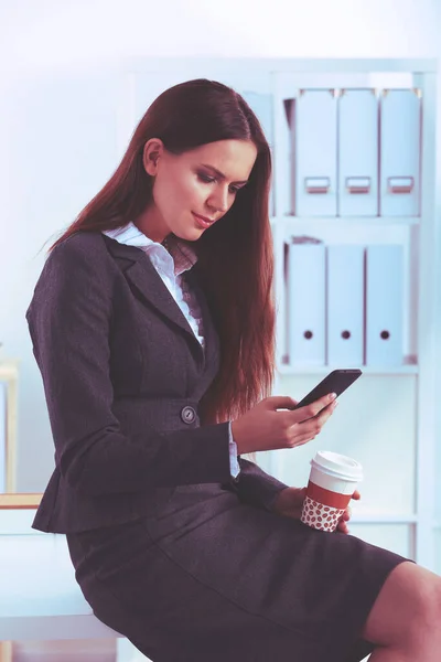 Businesswoman sending message with smartphone sitting — Stock Photo, Image