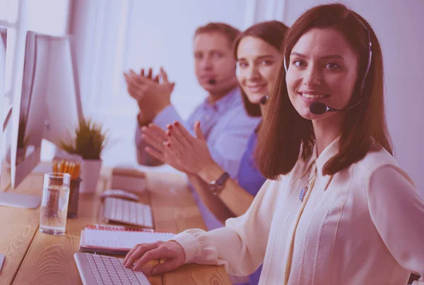 Porträt eines jungen Callcenter-Betreibers mit Headset und Kollegen, die im Hintergrund im Büro arbeiten — Stockfoto