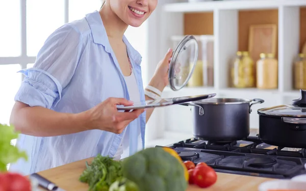 Jovem usando um computador tablet para cozinhar em sua cozinha. — Fotografia de Stock