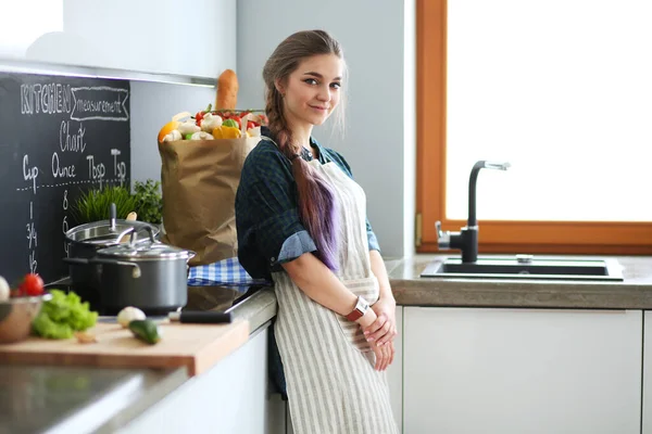 Junge Frau steht am Herd in der Küche . — Stockfoto