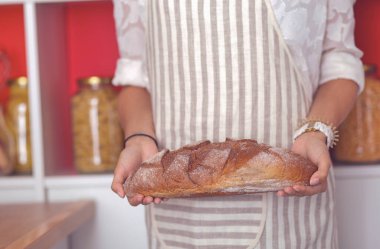 Genç bir kadın mutfağında lezzetli taze ekmek tutuyor.