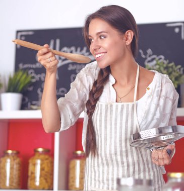 Mutfakta ahşap kaşıkla yemek pişiren kadın
