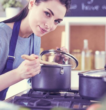 Mutfakta ahşap kaşıkla yemek pişiren kadın
