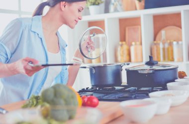 Mutfakta sobanın yanında duran genç bir kadın.