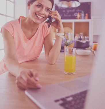 Mutfakta dizüstü bilgisayara benzeyen tariflerle gülümseyen genç bir kadın. Gıda blogcusu kavramı