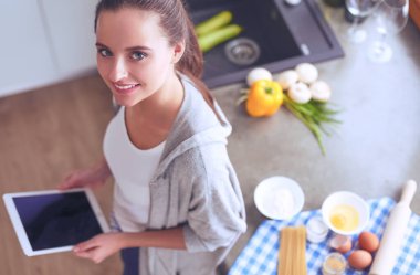 Tablette tarifi takip eden bir kadın evde yemek pişiriyor.