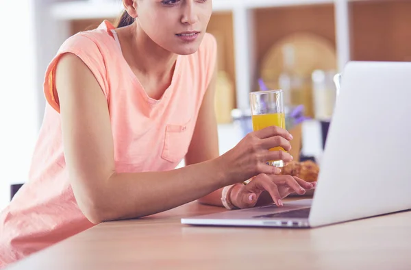Молодая женщина на кухне с ноутбуком компьютер ищет рецепты, улыбаясь. Концепция пищевого блогера — стоковое фото
