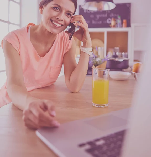 Ung kvinna i köket med bärbar dator ser recept, leende. Begreppet livsmedelsbloggare — Stockfoto