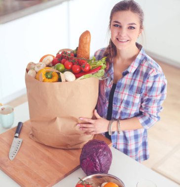 Elinde sebzeli alışveriş torbası tutan genç bir kadın. .