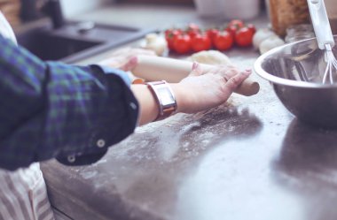 Güzel bir kadın mutfakta pasta pişiriyor. Masanın yanında duruyor..