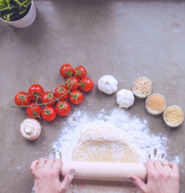 Güzel bir kadın mutfakta pasta pişiriyor. Masanın yanında duruyor..