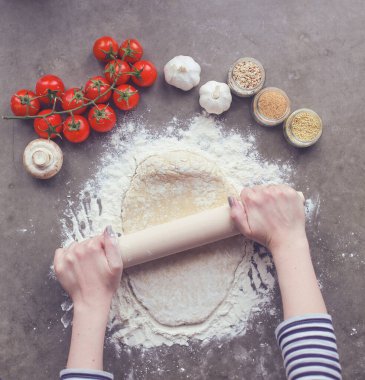 Güzel bir kadın mutfakta pasta pişiriyor. Masanın yanında duruyor..