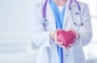 Kalbi tutan steteskoplu bir doktor, beyaz arka planda izole edilmiş.