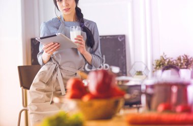 Tablette tarifi takip eden bir kadın evde yemek pişiriyor.