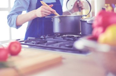 Mutfakta ahşap kaşıkla yemek pişiren kadın