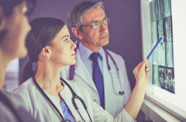 Bir grup doktor bir klinikte röntgenleri inceliyor, teşhis koymayı düşünüyorlar.