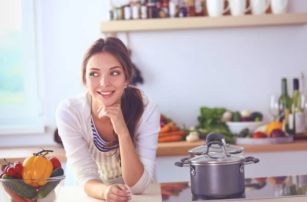 Mujer joven de pie cerca de escritorio en la cocina —  Fotos de Stock