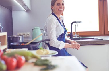 Mutfakta sobanın yanında duran genç bir kadın.