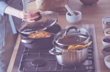 Evdeki mutfakta yemek pişiren güzel genç bir kadın..