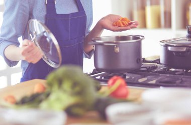 Mutfakta ahşap kaşıkla yemek pişiren kadın