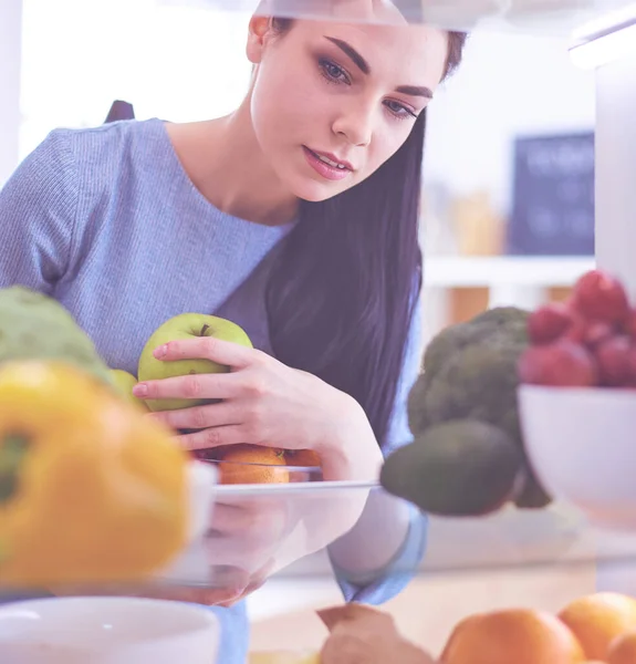 Mosolygó nő vesz egy friss gyümölcsöt ki a hűtőből, egészséges étel koncepció. — Stock Fotó