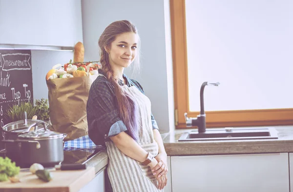 Mladá žena stojí u sporáku v kuchyni — Stock fotografie